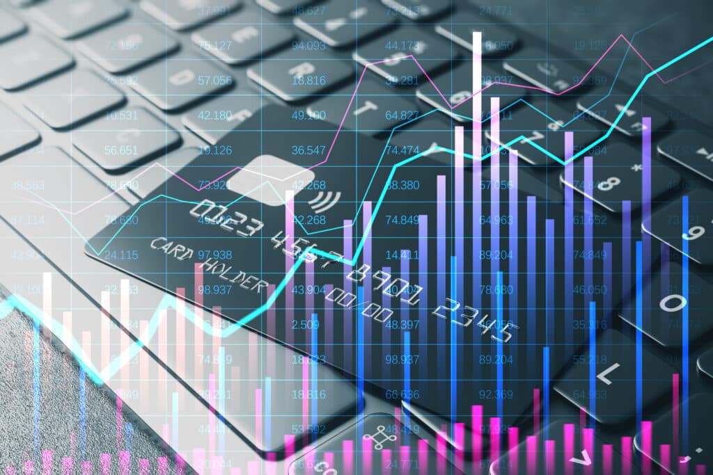 A credit card on a computer keyboard is overlaid with colorful financial graphs and bar charts, symbolizing online transactions, fintech, and digital financial data analysis.
